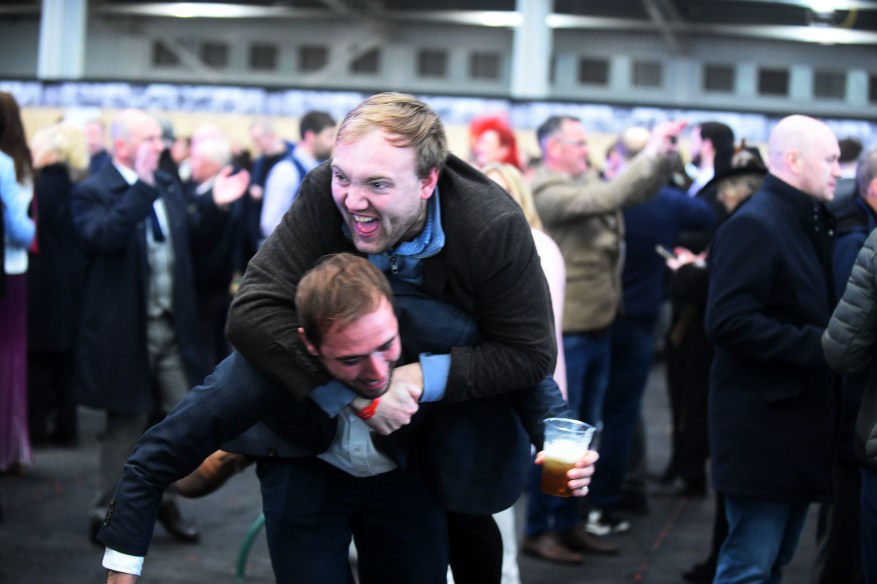 Aintree Revelers Get Into The Party Spirit At The Grand National As Racers Enjoy Booze And Plucky Frosts. A Man In A Suit And Boots Celebrated A Big Win By Jumping On His Friend'S Back.